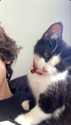 a woman holding a black and white cat in her lap while looking at the camera