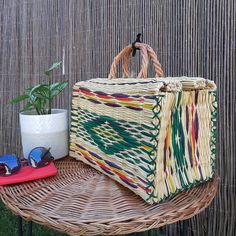 a wicker bag sitting on top of a table next to sunglasses and a potted plant