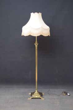 a lamp with a white shade on it and a cord plugged into the base