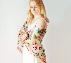 a woman in a white dress with flowers on her arm and arms around her waist