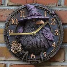 a clock with a bird wearing a witches hat on the side of a brick wall