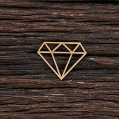 a gold diamond pin sitting on top of a wooden table next to wood planks