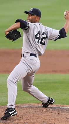 a baseball player pitching a ball on top of a field in the middle of a game