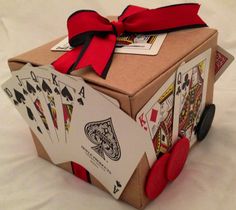 a cardboard box with playing cards tied to the side and a red bow on top