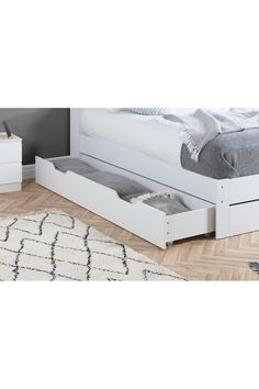 a white bed with two drawers in the bottom and one drawer open on each side