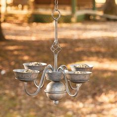 a metal chandelier with four bowls hanging from it's sides in a park