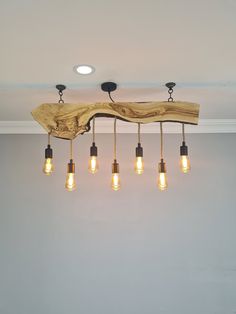 a wooden light fixture with five bulbs hanging from it's side and four lights on each end