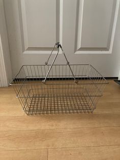 a metal basket sitting on the floor in front of a door