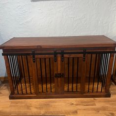 a wooden dog crate sitting on top of a hard wood floor next to a wall