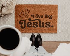 someone is sitting on the floor with their feet up next to a door mat that says love like jesus