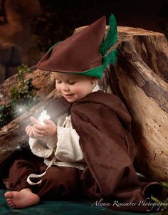 a baby dressed in a wizard costume sitting on the ground