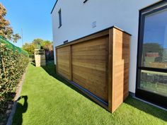 an outside view of a house with artificial grass and wooden fenced in area next to it