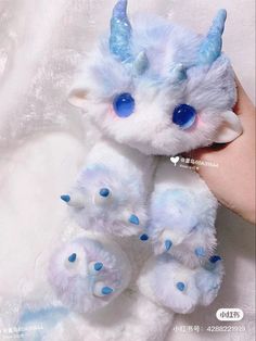 a small white stuffed animal with blue eyes