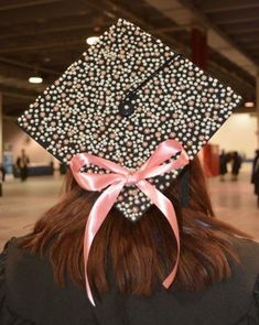 a woman wearing a graduation cap with pearls on it's side and pink ribbon