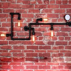 a brick wall with some lights hanging from it's sides and pipes running down the side