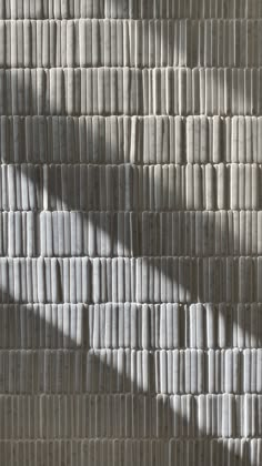 the shadow of a person standing in front of a wall made out of strips of paper