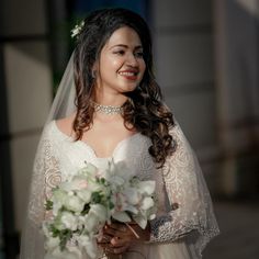 a bride smiles as she holds her bouquet