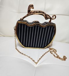 This chic bag is a fashionista's dream. You will love the structured body that features faux gold hardware with a top latch closure. The handle resembles a jaguar and feel free to rock it with or without the chain strap. The open compartment is spacious for a small bag. Available color: Black Chic Gold Clutch With Metal Hardware, Trendy Evening Bag With Gold-tone Hardware And Top Handle, Chic Gold Satchel For Party, Trendy Handheld Box Bag With Gold-tone Hardware, Gold Satchel With Gold-tone Hardware For Party, Trendy Gold Satchel For Formal Occasions, Trendy Gold Satchel For Party, Gold Shoulder Bag With Detachable Strap For Fashion, Gold Satchel With Metal Hardware For Evening