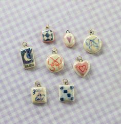 six charms with different designs on them sitting on a checkered cloth tableclothed surface