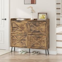 a wooden cabinet sitting in the corner of a room with shoes on the floor next to it