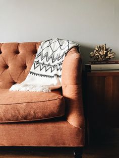 a brown couch sitting next to a table with a pillow on it's back