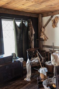 an old fashioned room with clothes hanging on the wall and other items sitting in baskets