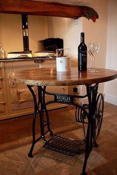 an old sewing machine table with wine glasses on it and a bottle of wine in the background