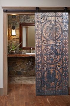 an open door leading to a bathroom with stone wall and wood flooring in it