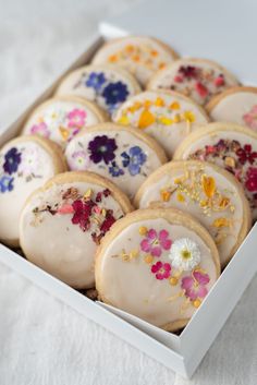 a box filled with lots of frosted cookies covered in sprinkles and flowers