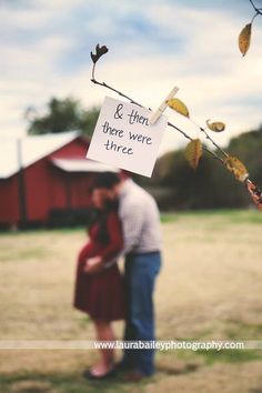 a man and woman standing next to each other under a tree with a sign on it