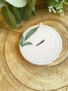 a white clock sitting on top of a wooden table next to flowers and greenery