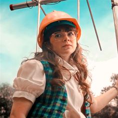 a woman wearing a hard hat and glasses holding a metal pole with two poles attached to it