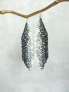 These long beaded earrings are inspired by the black, white and silver patters. Handcrafted with meticulous attention to detail, they exude timeless sophistication. Perfect for adding a touch of celestial charm to any ensemble, these earrings are sure to become a cherished addition to your jewelry collection. Dimensions: - Length: 13 cm (5 inches) - Width: 3 cm (1.2 inches) Bohemian White Earrings With Black Beads, White Dangle Jewelry With Black Beads, White Silver Beaded Drop Earrings, White Drop Earrings With Black Beads, White Beaded Earrings With Black Beads, White Bohemian Beaded Earrings With Silver Beads, Bohemian White Beaded Earrings With Silver Beads, White Bohemian Beaded Earrings With Black Beads, White Chandelier Earrings With Dangling Beads For Festivals