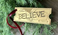 a christmas ornament hanging from the side of a tree with red ribbon around it