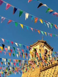 multicolored flags are hanging from the top of a building