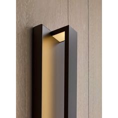 a wall light that is mounted on the side of a wooden paneled wall,