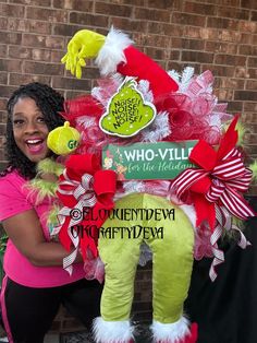 a woman standing next to a christmas tree with the grinch on it's head