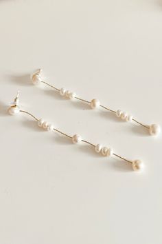 three pairs of pearled earrings on a white surface with pearls hanging from them, all in different shapes and sizes