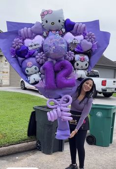 a woman standing in front of a bunch of purple balloons and stuffed animals on top of it