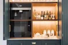 an open cabinet with many bottles and glasses on the shelves, including a coffee maker