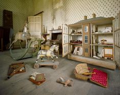 an old fashioned doll house with wooden furniture and horse figurines on the floor