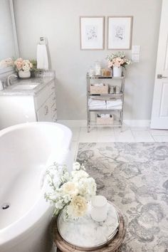 a white bath tub sitting in a bathroom next to a sink and toilet with flowers on it