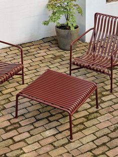 two chairs and a coffee table on a brick patio with a potted plant in the corner