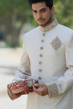 a man wearing a white sherve with red and gold details on his jacket