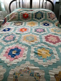 a bed with a quilt on top of it and a window in the back ground