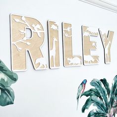 the name riley is made out of wooden letters with tropical leaves and birds on them