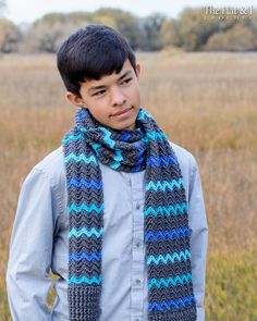 a young boy wearing a blue and gray scarf in the middle of an open field