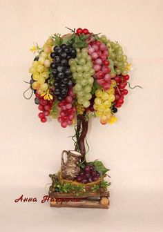 a vase filled with lots of grapes on top of a wooden table next to a tree