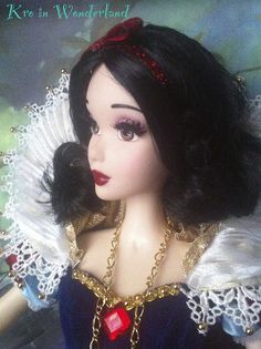 a close up of a doll wearing a blue dress and red headband with gold chains