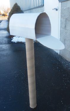 a white mailbox sitting in the middle of a parking lot next to a building